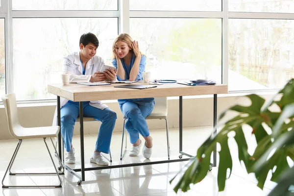 Médico masculino e assistente médico feminino sentados à mesa durante o intervalo na clínica — Fotografia de Stock