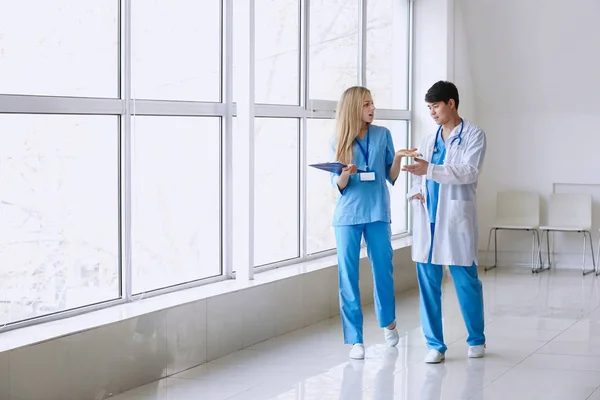 Male doctor and female medical assistant walking down the corridor in clinic — Stock Photo, Image