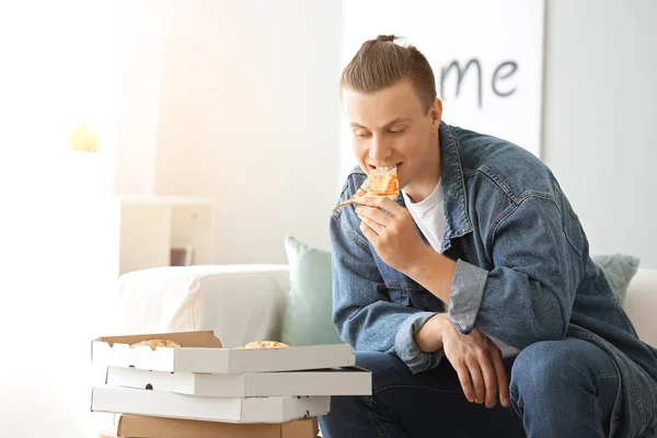 Pohledný muž, který jedl doma chutnou pizzu — Stock fotografie