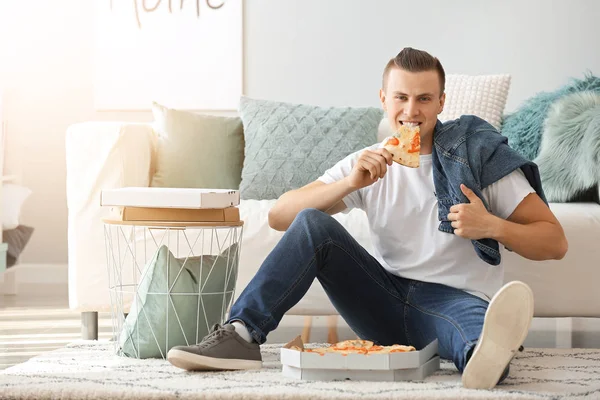 Handsome man eating tasty pizza at home — Stock Photo, Image