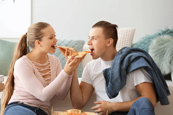 Young couple eating tasty pizza at home