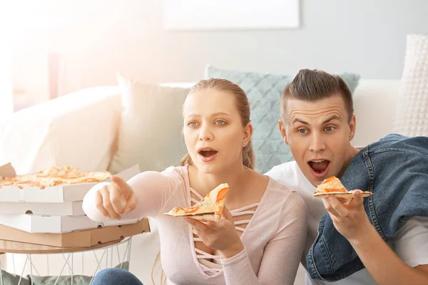 Casal emocional comer pizza saborosa enquanto assiste TV em casa — Fotografia de Stock