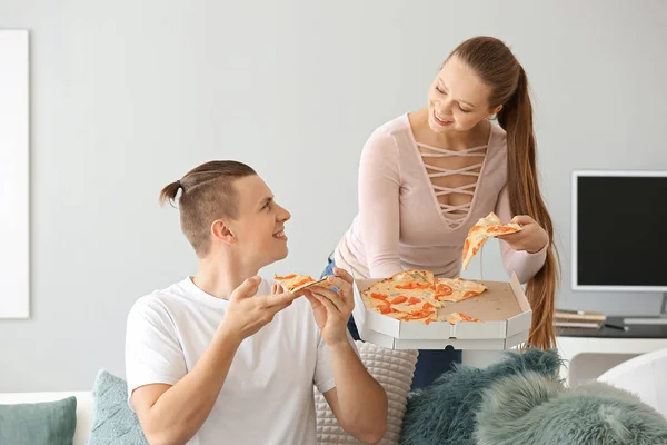 Jovem casal comer pizza saborosa em casa — Fotografia de Stock