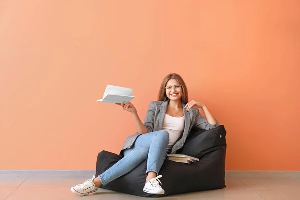 Bella giovane donna con libri vicino alla parete a colori — Foto Stock