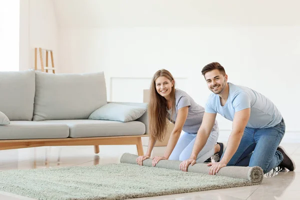 Junges Paar rollt Teppich auf dem Boden aus — Stockfoto