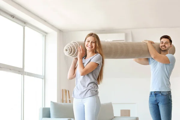 Junges Paar mit Teppich in neuer Wohnung — Stockfoto