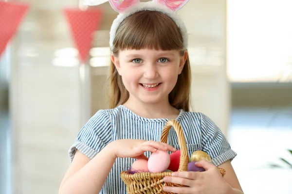 Little girl with basket full of painted Easter eggs at home — Stock Photo, Image