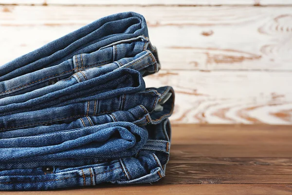 Pila de pantalones vaqueros en mesa de madera —  Fotos de Stock