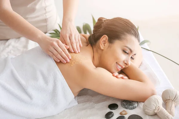 Young woman undergoing treatment with body scrub in spa salon — Stock Photo, Image