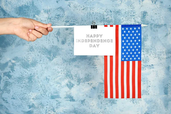 Kvinnlig hand Holding USA flagga och kort med text Lycklig självständighetsdagen på färg bakgrund — Stockfoto