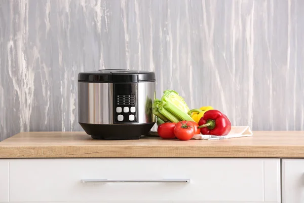 Modern multi cooker with vegetables on kitchen table — Stock Photo, Image
