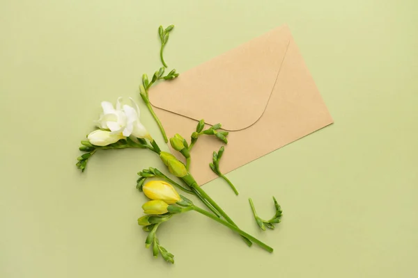 Beautiful freesia flowers and envelope on color background — Stock Photo, Image