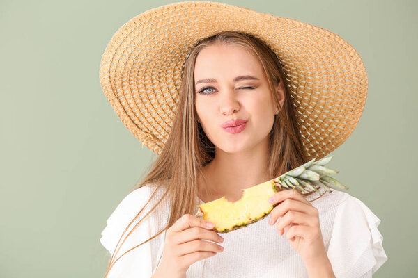 Beautiful young woman eating pineapple on color background