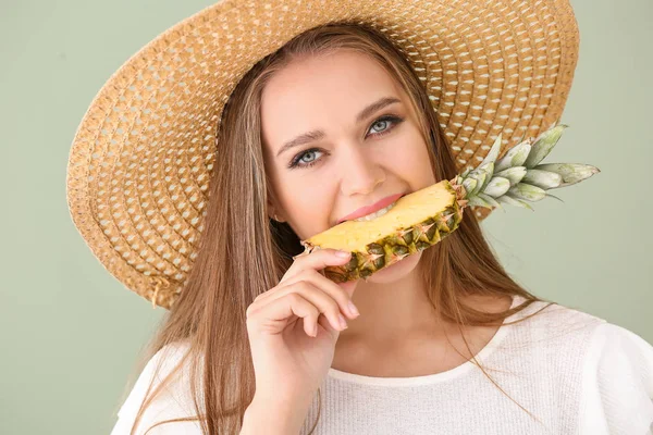 Beautiful young woman eating pineapple on color background — Stock Photo, Image
