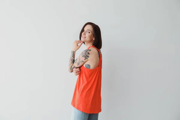Elegante tatuado mulher no luz fundo — Fotografia de Stock