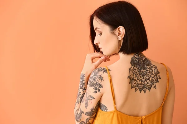 Mulher tatuada bonita no fundo da cor — Fotografia de Stock
