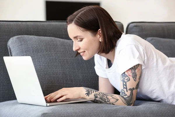 Belle femme tatouée travaillant sur un ordinateur portable à la maison — Photo