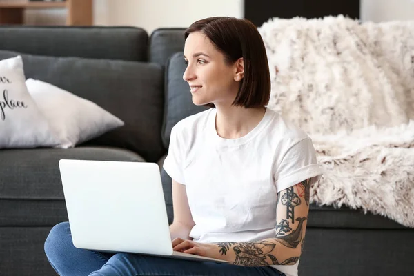 Beautiful tattooed woman working on laptop at home — Stock Photo, Image