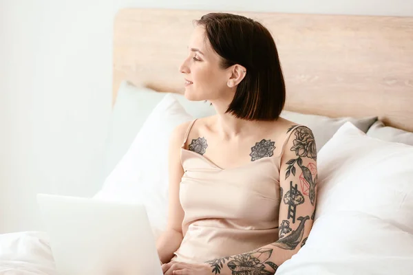 Manhã da bela mulher tatuada com laptop no quarto — Fotografia de Stock