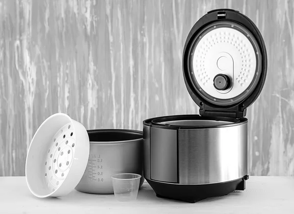 Modern multi cooker with accessories on table against grey background — Stock Photo, Image