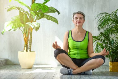 Sportif olgun kadın evde meditasyon