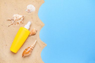 Renk arka planda kum ve deniz kabukları ile güneş koruma kremi