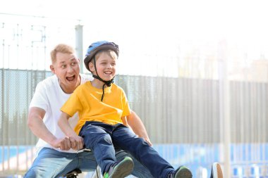 Baba ve küçük oğlu açık havada bisiklete biniyor.