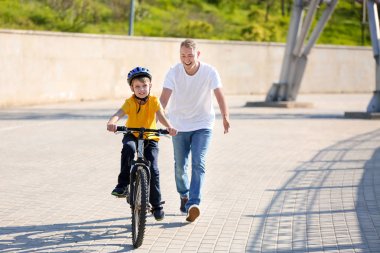 Baba oğluna dışarıda bisiklete binmeyi öğretiyor.
