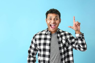 Renkli arka planda işaret parmağı yükseltilmiş yakışıklı adam