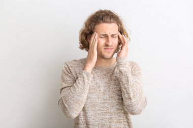 Beyaz arka planda baş ağrısı çeken genç bir adam.
