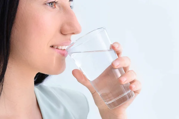 Woman drinking fresh water on light background — Stock Photo, Image