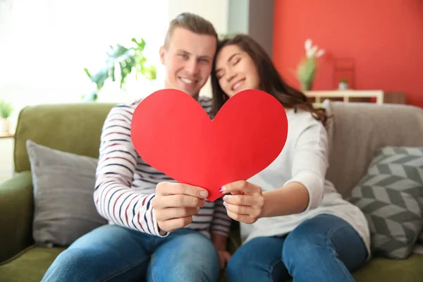 Feliz pareja joven con corazón de papel en casa — Foto de Stock