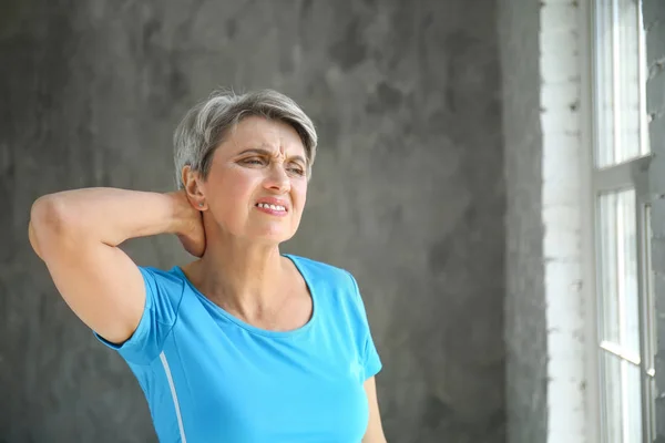 Mulher madura que sofre de dor no pescoço em casa — Fotografia de Stock