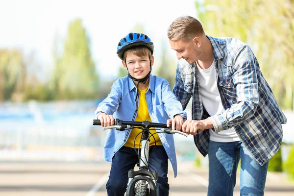 Father teaching his son to ride bicycle outdoors — Stock Photo, Image