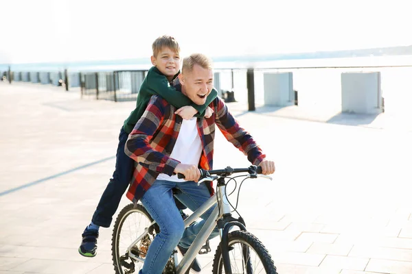 Father and his little son riding bicycle outdoors — Stock Photo, Image