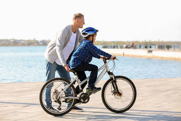 Padre enseñando a su hijo a andar en bicicleta al aire libre — Foto de Stock