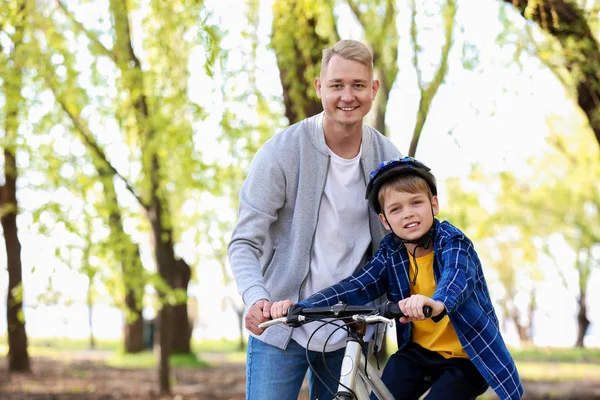 Pai ensinando seu filho a andar de bicicleta ao ar livre — Fotografia de Stock