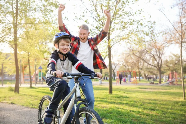 Pai orgulhoso de seu filho que aprendeu a andar de bicicleta ao ar livre — Fotografia de Stock