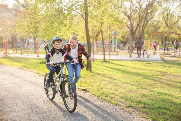 Padre enseñando a su hijo a andar en bicicleta al aire libre — Foto de Stock