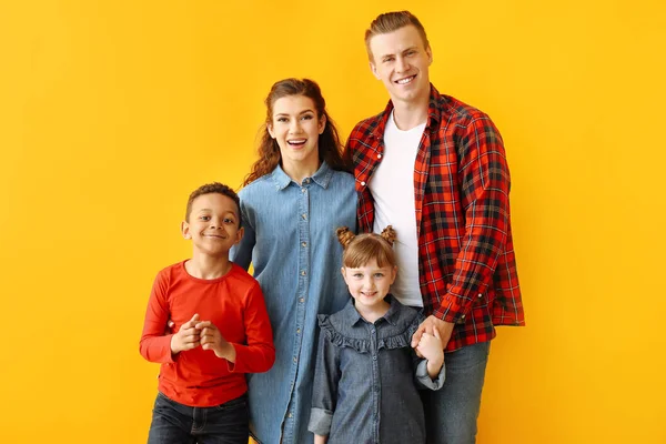 Счастливая пара с маленькими приемными детьми на цветном фоне — стоковое фото
