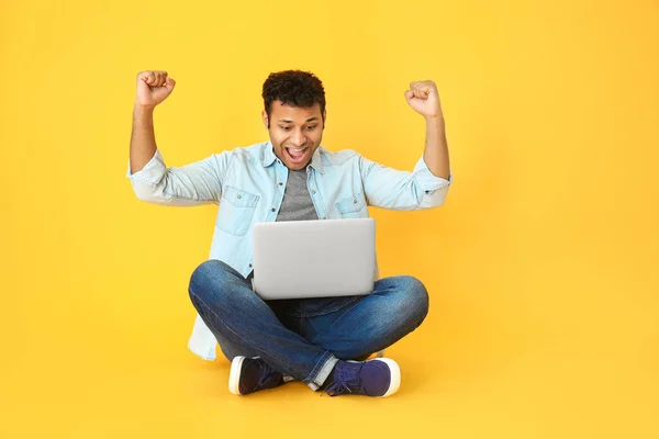 Happy man with laptop on color background