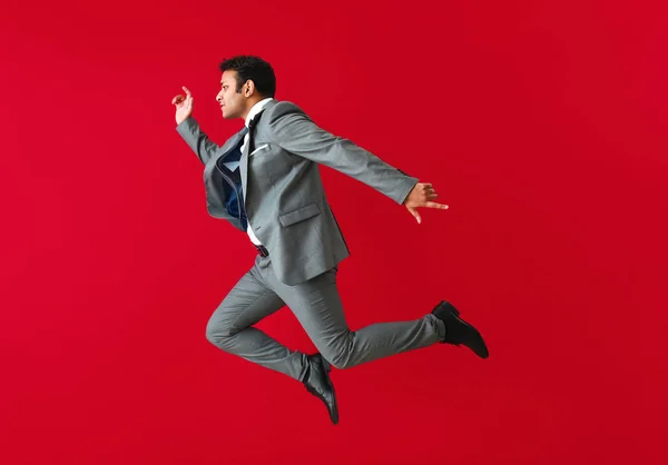 Saltando hombre de negocios en el fondo de color —  Fotos de Stock