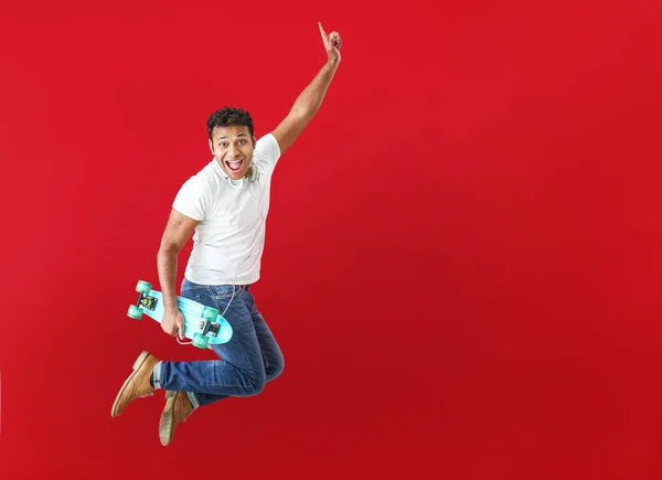 Cool jumping man with skateboard on color background — Stock Photo, Image