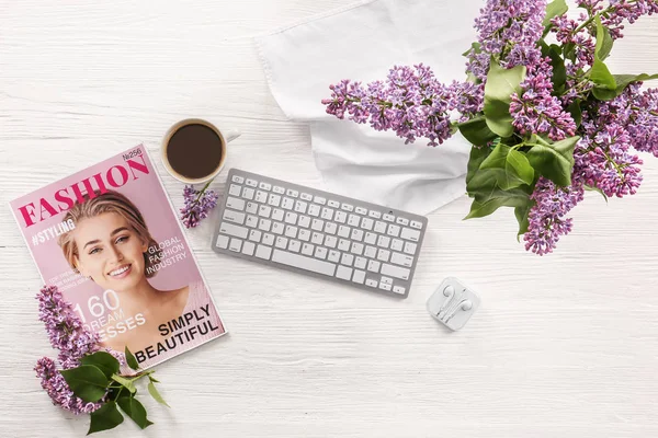 Lugar de trabajo con teclado de ordenador, revista de moda y hermosas flores lila sobre fondo de madera blanca —  Fotos de Stock