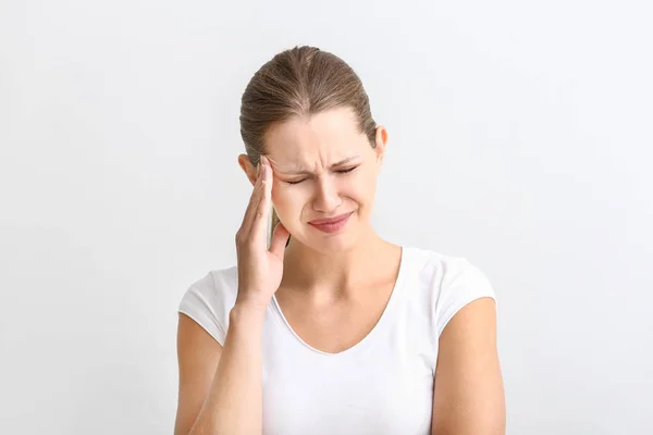 Mujer joven que sufre de dolor de cabeza sobre fondo blanco —  Fotos de Stock