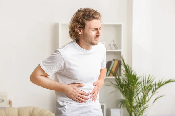 Young man suffering from abdominal pain at home — Stock Photo, Image