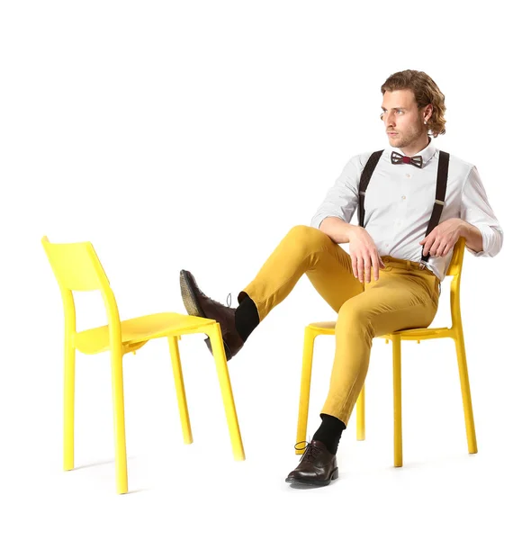Stylish young man sitting on chair against white background — Stock Photo, Image