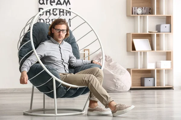 Elegante joven sentado en sillón en casa — Foto de Stock