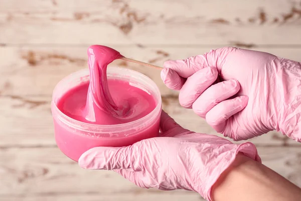 Female hands with sugaring paste for hair removal on wooden background
