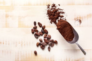 Ahşap arka planda kakao tozu ve fasulye ile Kepçe